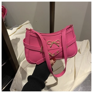 Detail of hot pink baguette bag with gold bow clasp and decorative leather strap