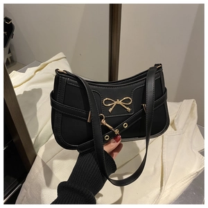 Detail of a vintage black leather underarm bag with a golden butterfly metal clasp