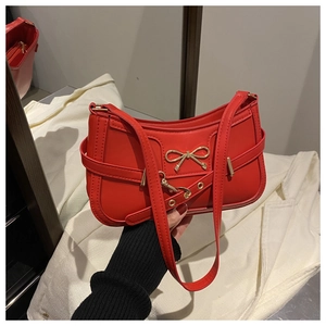 Detail of red leather shoulder bag featuring a gold butterfly metal buckle and adjustable strap