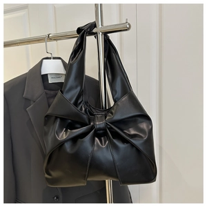 Close-up of the elegant large bow pleated design on this black faux leather handbag