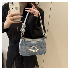 Detail of glitter blue denim bag with silver bow, faux pearl charms and woven rope handle