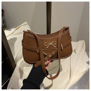 Detailed view of the brown shoulder bag with a gold butterfly metal clasp and smooth texture