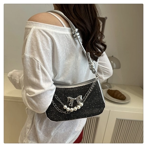 Detail of black shimmer fabric shoulder bag with silver bow and pearl chain strap