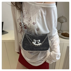 Close-up of Y2K style black denim crossbody bag with silver bow and pearl details