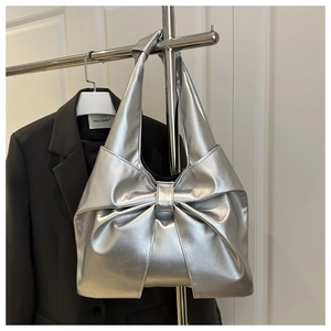 Detail of silver metallic bow-shaped handbag on a hanger with sleek modern finish