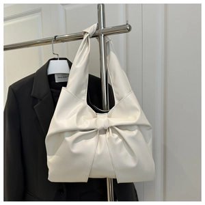 Detail of cream tote bag with large decorative bow and knotted faux leather shoulder strap