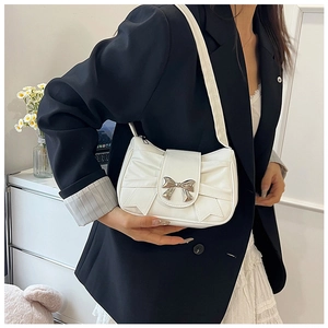 Détail du sac à bandoulière blanc plissé avec fermoir nœud argenté porté par le mannequin