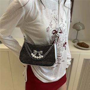 Dark gray sequin shoulder bag with silver bow, pearls and chain detail on a model