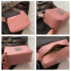 Detail view of pink PU leather crossbody bag with wide ethnic strap and silver SM metal logo