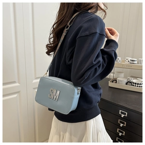 Detail of light blue crossbody bag with rhinestone SM logo and printed wide strap