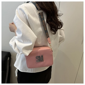 Detail of pink crossbody bag with sparkling SM crystal letters and wide woven shoulder strap