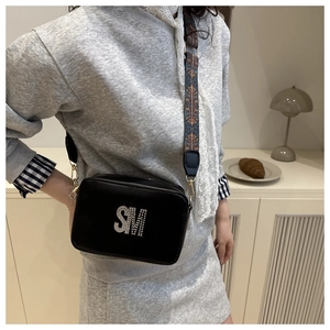 Detail of black crossbody bag with rhinestone SM logo and vintage wide shoulder strap