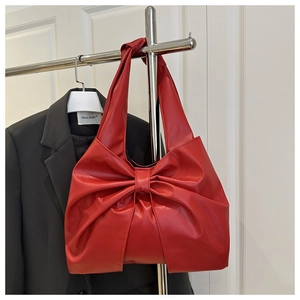 Detail of red tote bag featuring a large decorative bow and matte leather texture