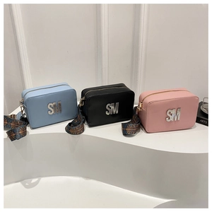 Detailed view of three crossbody square bags with rhinestone letters and woven straps