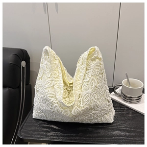 Gros plan d'un sac cabas en dentelle beige montrant des motifs floraux au crochet