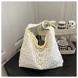 Détail du sac cabas en dentelle blanche avec motifs floraux, papillons et doublure beige