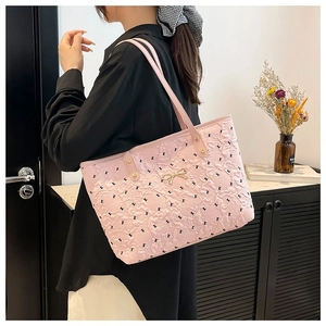 Sac cabas plissé rose avec nœud doré et broderie porté par un mannequin