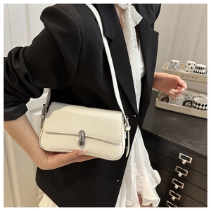 Detail of off-white leather underarm bag with silver twist lock and adjustable strap