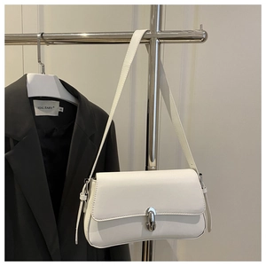 Detail view of white minimalist shoulder bag with silver clasp hanging next to a blazer