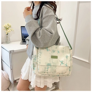 Detail of a beige canvas messenger bag featuring green butterfly prints and adjustable strap