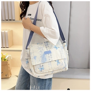 Detail of white messenger bag featuring blue butterfly prints and ink bamboo patterns