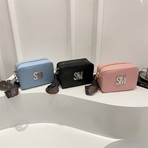Three camera-style crossbody bags with rhinestone SM letters and wide patterned straps