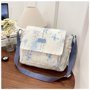 Detail of floral canvas shoulder bag featuring blue calligraphy pattern and nylon strap
