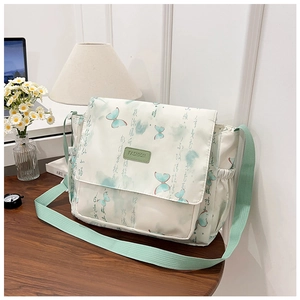 Detail of cream canvas bag with green butterfly print and adjustable strap on wood desk