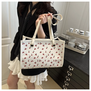 Gros plan du sac fourre-tout blanc avec imprimés cerises et doubles poignées