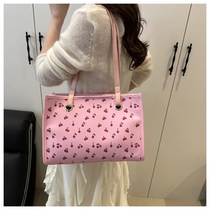 Shoulder bag detail featuring cherry print and golden metal ring handle attachment