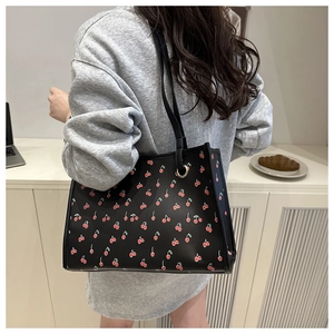 Detail shot of black cherry print tote bag worn on shoulder for summer fashion