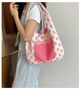 Détail du sac cabas en toile avec motifs nœuds rouges et poche à bordure dentelle