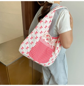 Détail d'un sac cabas avec motifs nœuds rouges et poche à carreaux avec cordon