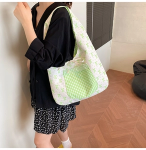 Sac fourre-tout à fleurs avec nœuds verts et poche vichy porté à l'épaule par un mannequin