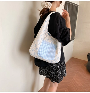 Détail du sac cabas en toile avec motifs de nœuds bleus et poche vichy bordée de dentelle