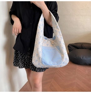Détail d'un sac cabas en toile à fleurs avec imprimé nœud bleu et poche en dentelle
