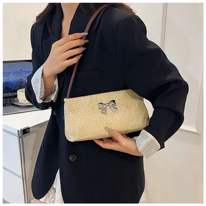 Detail of beige woven straw shoulder bag with silver bow buckle and dark brown strap