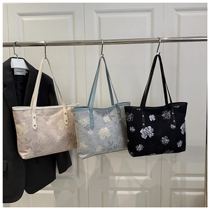 Détail des sacs cabas à motifs floraux en abricot, bleu clair et noir avec fines lanières