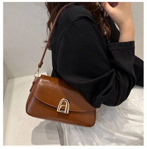 Détail du sac bandoulière marron vintage avec une boucle en métal doré en forme d'arche