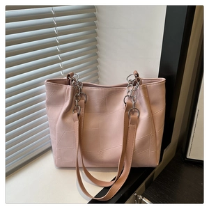 Detail of pink geometric textured tote bag with silver chain strap on white surface