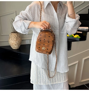 Détail du mini sac à dos marron avec motif d'ours et bandoulière en chaîne dorée