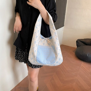 Sac cabas floral en toile avec poche vichy bleue et nœud porté par un mannequin