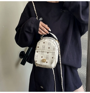 Détail d'un mini sac à dos beige avec imprimé ours et fermoir rotatif doré