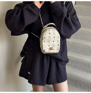 Mini sac à dos beige à motifs d'ours avec bandoulière chaîne dorée porté par un mannequin