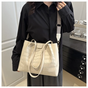 Detail of crocodile pattern tote bag with woven strap and handle on a model