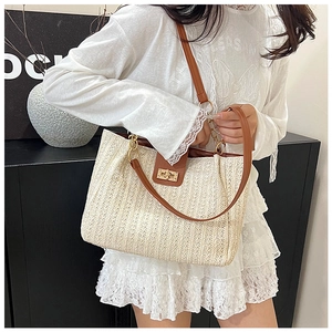 Détail du sac cabas en paille tissé main avec lanières en cuir marron et fermoir doré