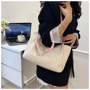 Détail du sac cabas en paille crème avec anse en cuir rose et chaîne dorée à l'épaule