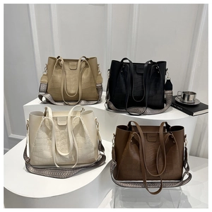 Detail of four crocodile embossed tote bags in khaki, black, cream, and dark brown colors