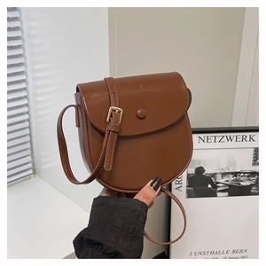 Detail of a brown semi-circle saddle bag with gold hardware and a long adjustable strap