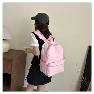 Detailed side view of pink canvas backpack featuring MRW lettering and mesh side pocket